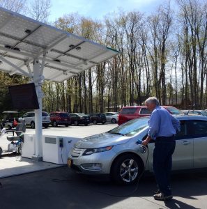 man pluging his electric car into Reinstein Woods' charging station