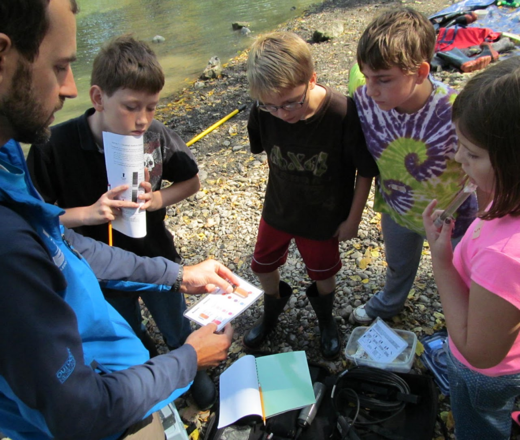Students examine a dissolved oxygen test at the riverbank